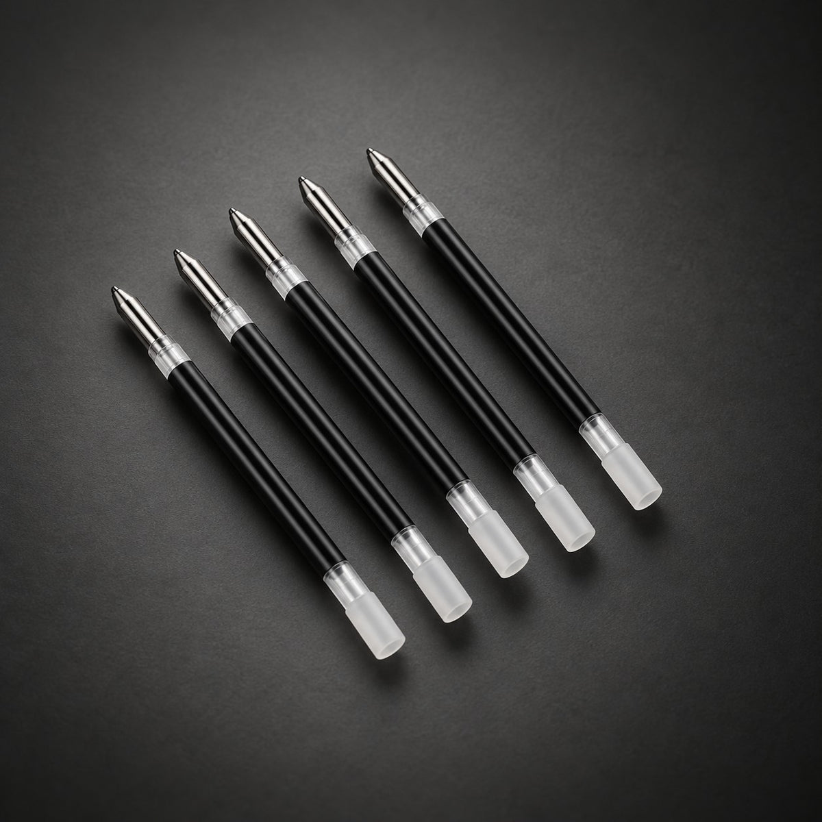 Five Scriben refills on a dark background